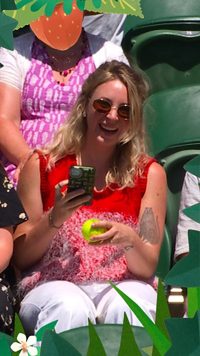 Fan holds the Wimbledon ball and takes a photo of it