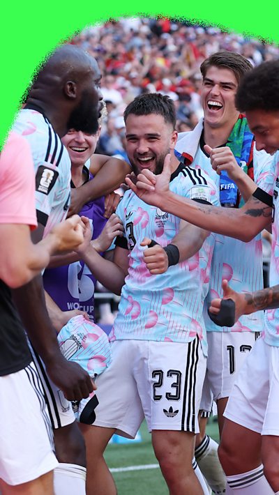 Belgium players celebrating a goal against America at the World Cup. They are wearing light blue shirts.