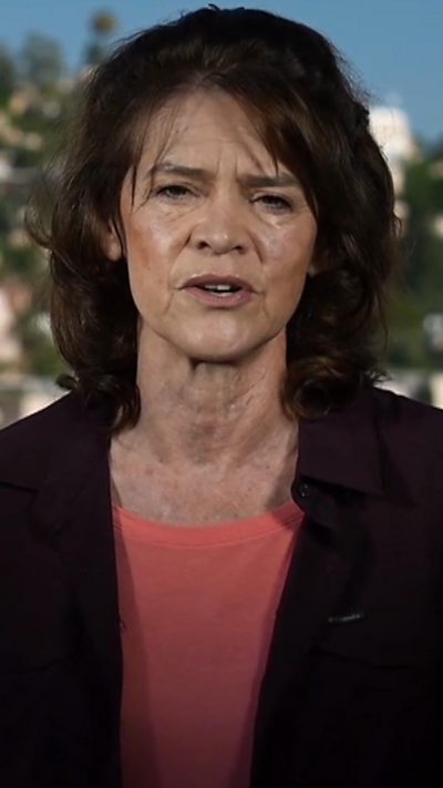 Barbara Plett Usher in a pink top and black blazer with trees behind her