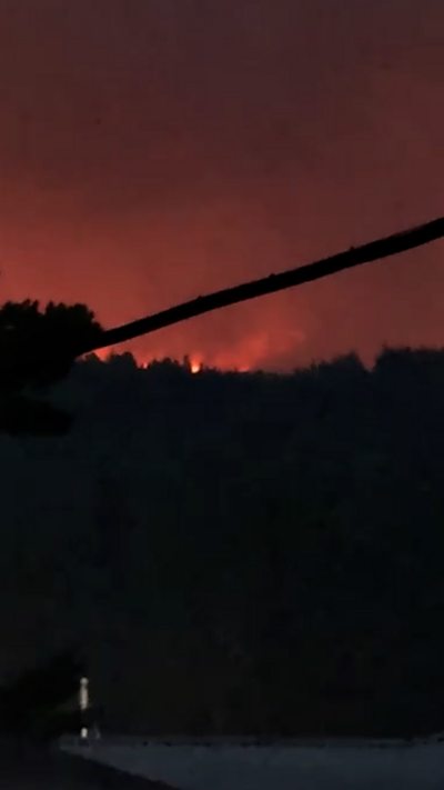 Flames in distance on a hill, filmed at night