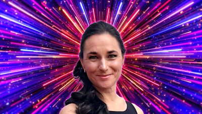 A woman with dark hair tied back smiles to camera, set against a backdrop of glittering pink, blue and purple rays of light