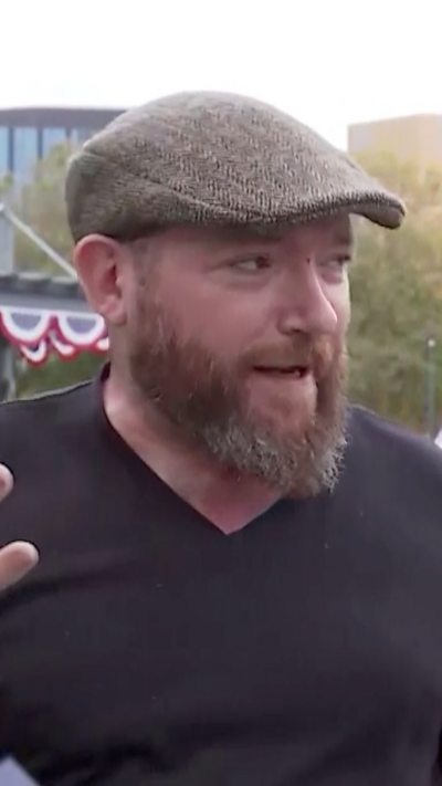A man with a beard and grey flat cap speaks to camera.