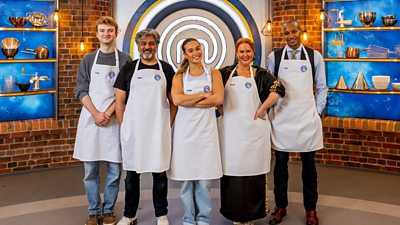 Five celebrity masterchef contestants line up in their white aprons and smile towards camera