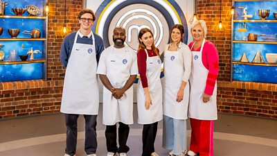 Five celebrity masterchef contestants line up in their white aprons and smile towards camera