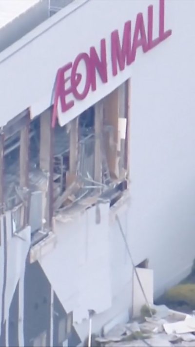 Damaged exterior walls below an Aeon Mall sign