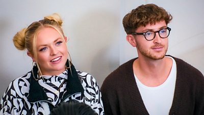 A woman and a man smiling looking away from camera