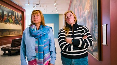 Rebecca and Daisy stood side by side inside an art gallery looking away from camera