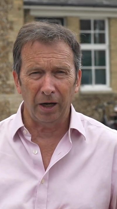 Male reporter wears a pink shirt with an open collar