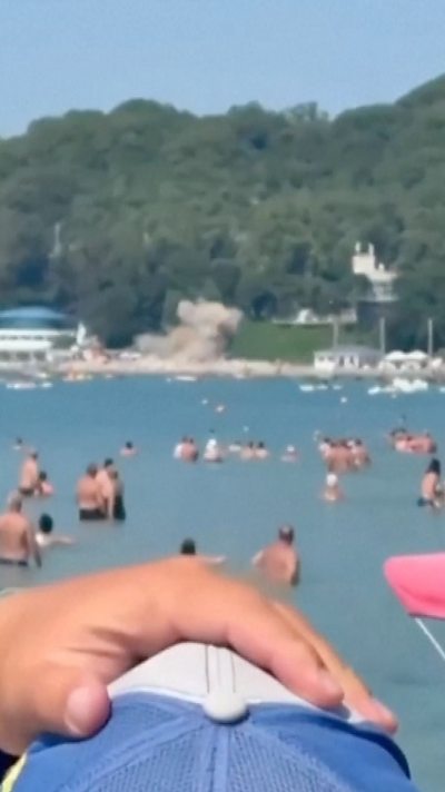 Explosion on a beach with many people in the sea.