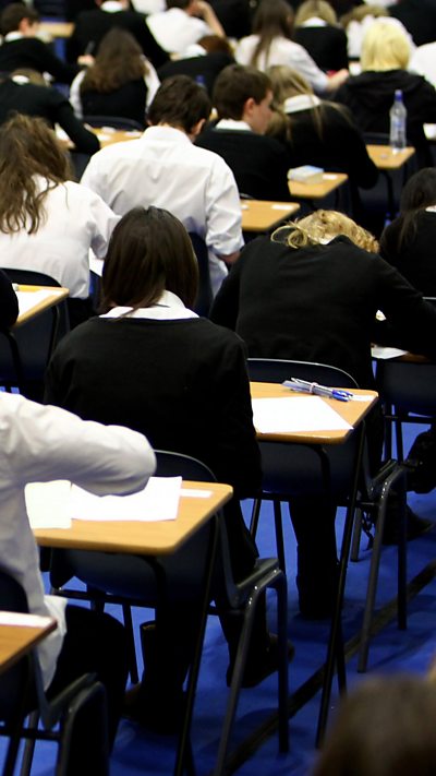 Back view of a row of students taking an exam in a school hall