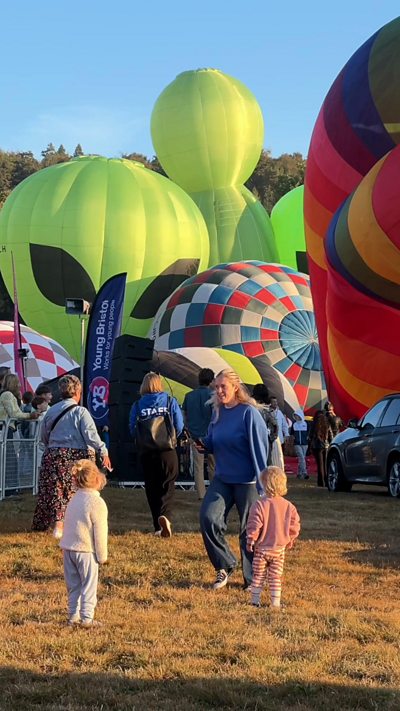 A woman stands in front of balloons inflating in Bristol.