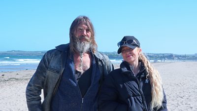 A man and a woman stood wrapped ip in jackets stood on a beach in Scotland