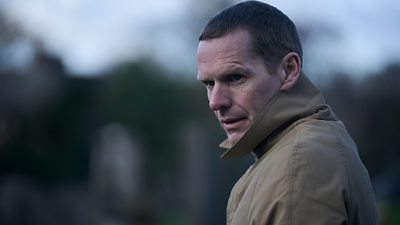 Scene from This City is Ours series 2. Close-up of Ozzie (Shaun Evans) standing outside, wearing a high-collared coat. 
