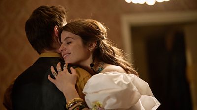 A woman in a puffy white dress hugging a man in a yellow shirt and green waistcoat