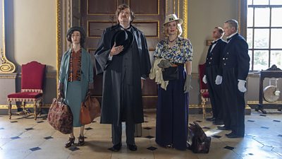 Bryony Hannah as Agatha Christie, Miles Jupp as G.K. Chesterton and Cara Theobold as Dorothy L. Sayers. The trio stand in a large entrance hall together, each with their luggage to hand, while two footmen in suits stand to attention alongside them,