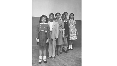 A black and white photograph of the schoolchildren in the Brown v. Board of Education case, who are all stood in a line.