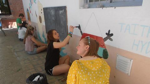 A group of girls painting a wall