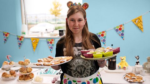 A girl holding cakes in a Children in Need cake sale