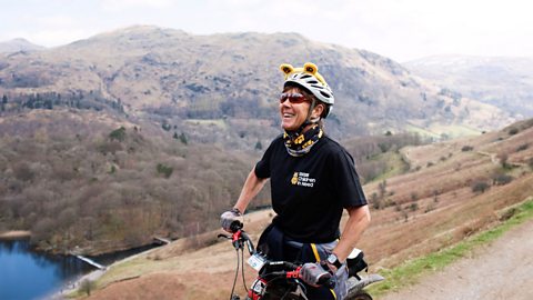 A woman on a bike wearing a Pudsey headband