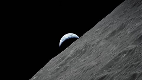 The Earth rising above the surface of the Moon.