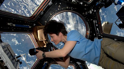 An astronaut looks through the windows of the ISS onto Earth below.