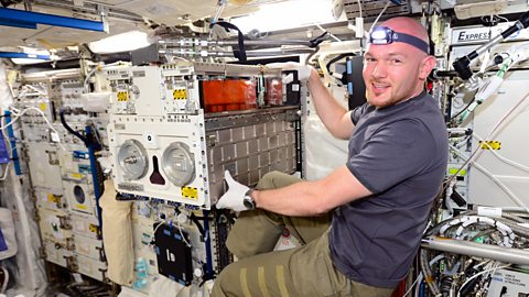 Astronaut Alexander Gerst moves laboratory equipment within the ISS.