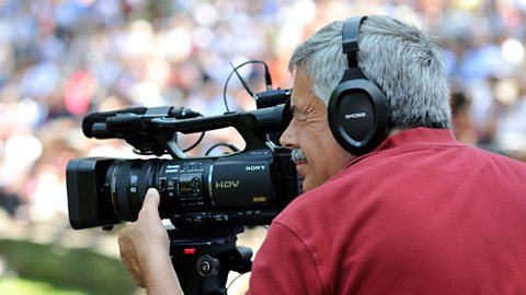 A camera operator using headphones to monitor sound