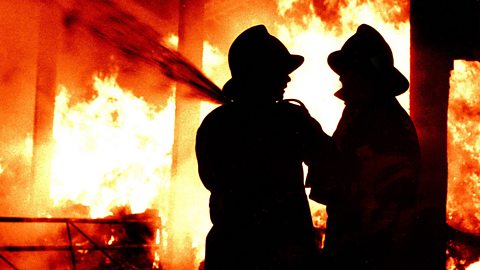 Firefighters attempting to put out a blaze with a hose.