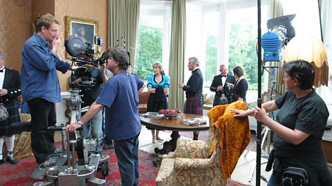 A film crew working in front of a large window.