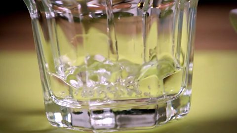 A glass being filled with vinegar