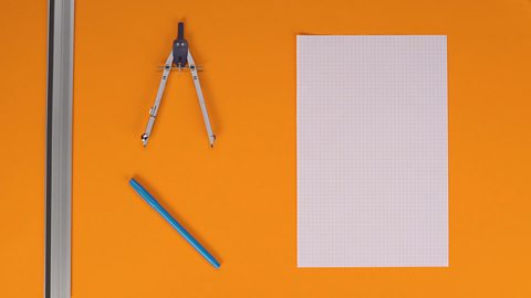 An image showing squared paper, a pen, a ruler and a compass.