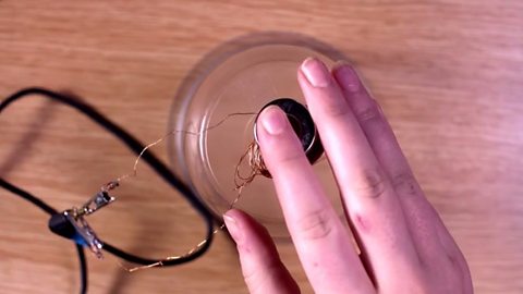 The magnet placed on top of the copper coil on top of the plastic cup