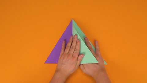 Someone sticking different coloured triangles together