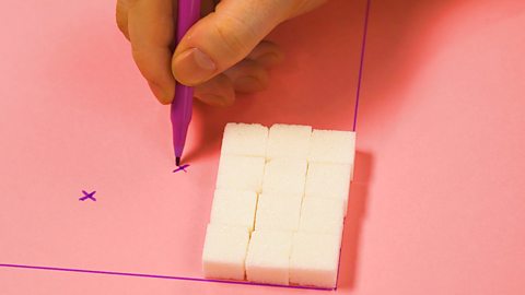 Someone putting a cross on the side of a stack of cubes