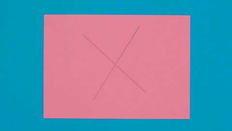 A drawing of two crossing lines on a piece of pink paper