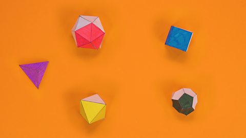 Paper tetrahedron, cube, octahedron, dodecahedron and icosahedron with coloured faces