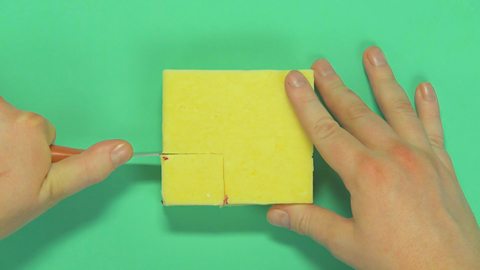 Someone cutting off a block of cheese