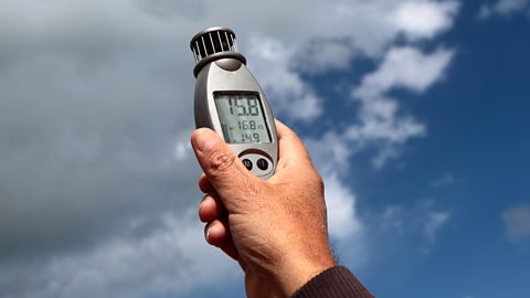 Holding up an anemometer in the wind.