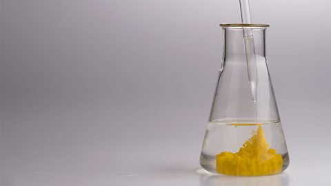 A yellow solid forming in a clear liquid inside a test tube