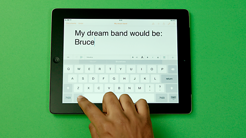 A person typing a list of who would be in their dream band.