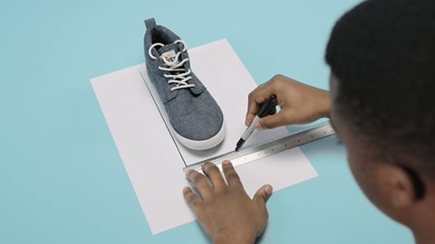 Stand on a sheet of paper and use a pen and a ruler to draw a rectangle around the trainer. 