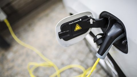 An electric car is being charged with a close up shot of the charging portal.