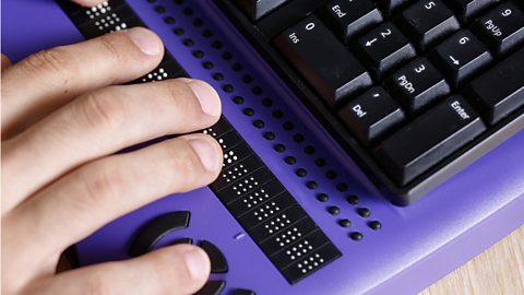 A blind person uses a computer with a braille keyboard.