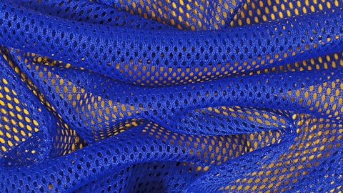 A close-up image of bright blue, crumpled, non-woven, bonded fabric on a yellow background.