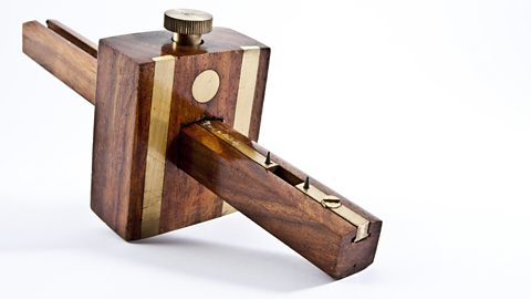 A dark wooden mortise gauge with a rectangular design in the centre.