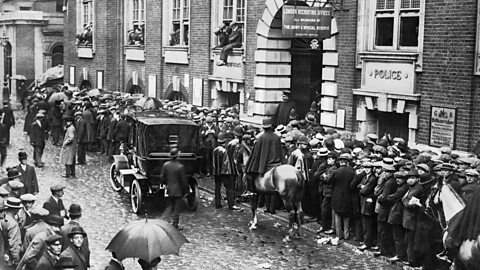 Young men queuing eagerly along a street outside a recruitment station in World War One