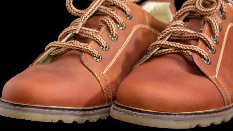 A close-up image of the toes of a pair of brown men’s shoes with eyelets.