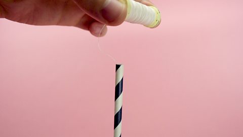 Threading cotton through straw.