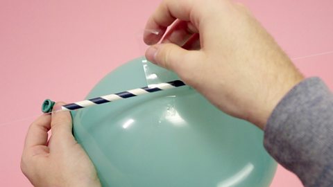 Tape the straw to the balloon.