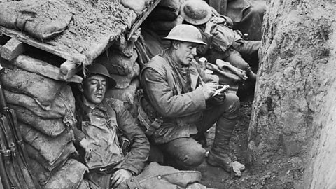 Canadian soldiers sleeping and writing letters in a World War One trench.